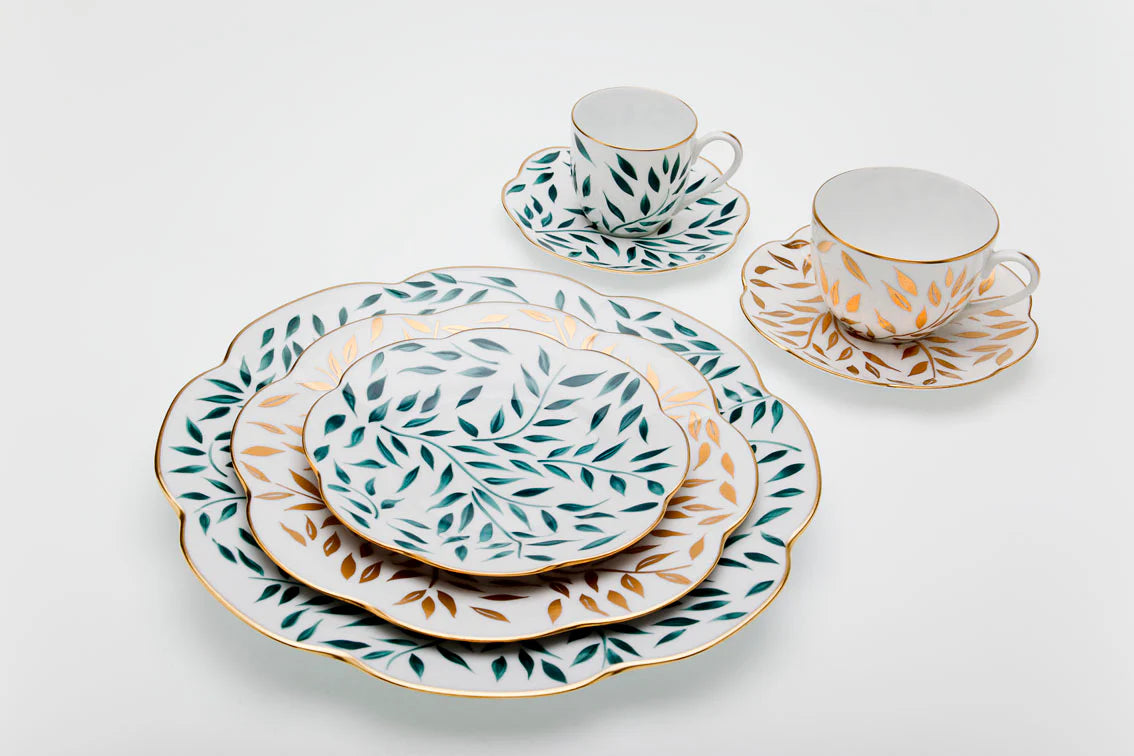 Olivier dinner plate in green with leaf patterns, surrounded by matching cups and saucers on a white background.