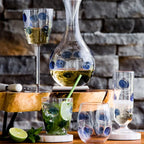 Drop blue stemless wine glass featuring a transparent design with blue dots, placed on a wooden surface.