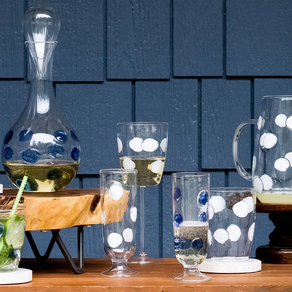 Drop white tall tumbler with blue and white polka dots, displayed alongside matching glassware on a wooden table.