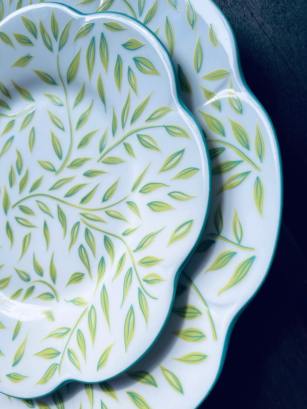 Olivier dessert plate in spring features a white base with green leaf patterns and a scalloped edge.