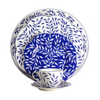 Olivier charger plate in blue featuring a leaf pattern on a white background, displayed with matching dinnerware.