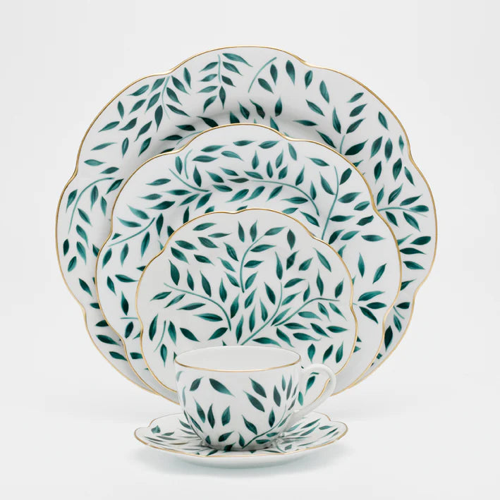 Olivier dinner plate in green with leaf patterns and gold trim, displayed among smaller plates and a cup.