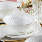 Pietra Serena cereal bowl in white, featuring a textured rim, placed on a table setting with elegant glassware and flowers.
