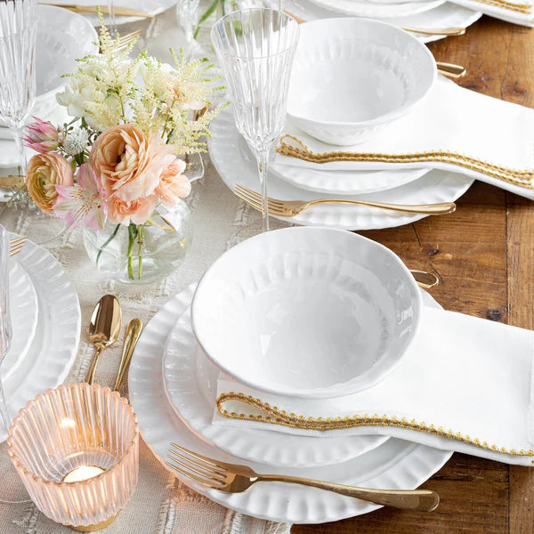 Pietra Serena cereal bowl in white ceramic, placed on a table setting with gold accents and floral arrangements.