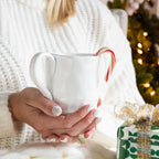 Pietra Serena mug held by a person, featuring a white ceramic design and a red and white candy cane.