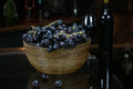 Salad and serving bowl, 11" diameter, filled with dark grapes, set on a black surface with a wine glass and bottle.