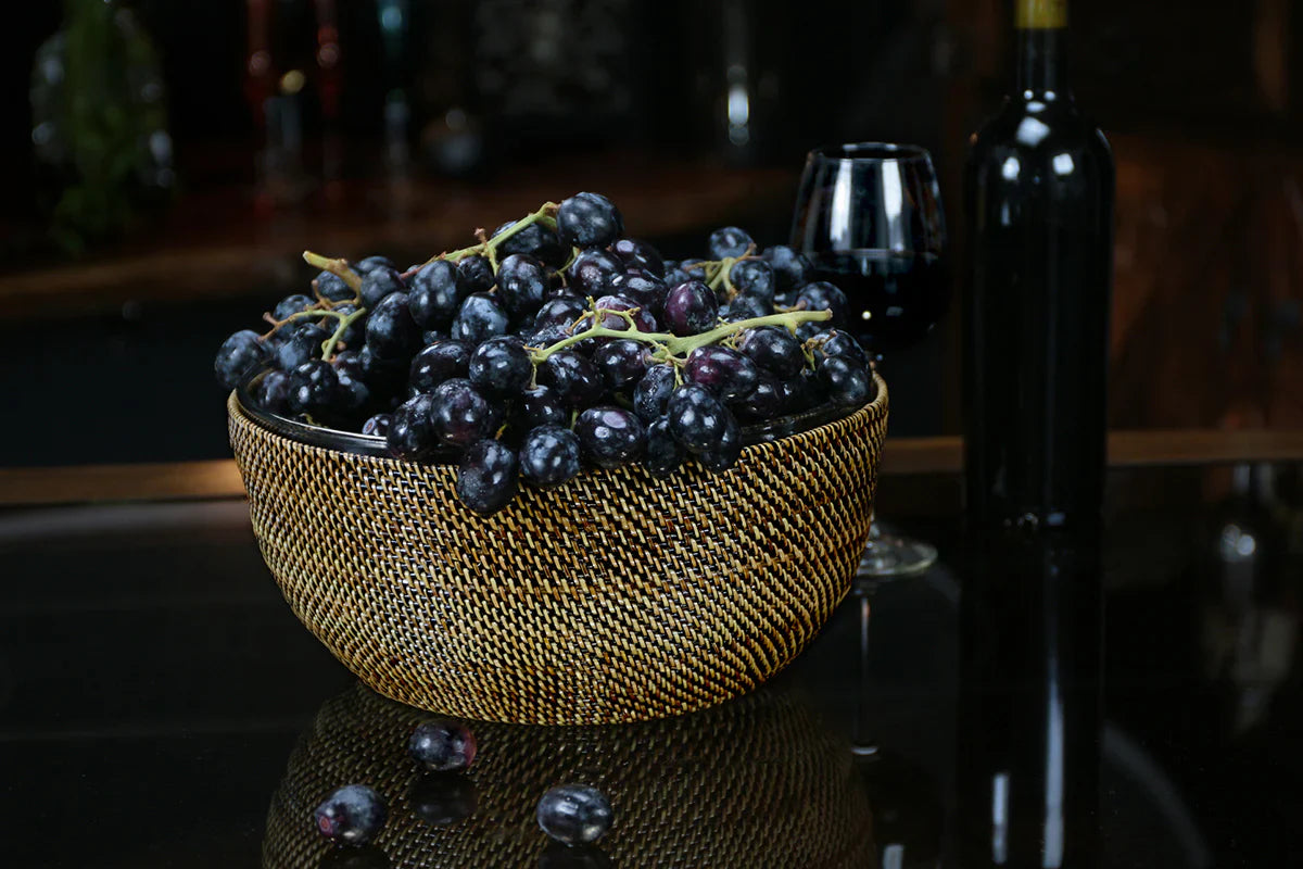 Salad and serving bowl, 11" diameter, filled with dark grapes, set on a black surface with a wine glass and bottle.