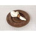 Set of four round plate chargers in natural woven material, featuring a textured brown finish and white napkin accent.