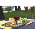 Rectangular serving tray with a glass bottom, featuring cheese, grapes, and two glasses on a textured surface.