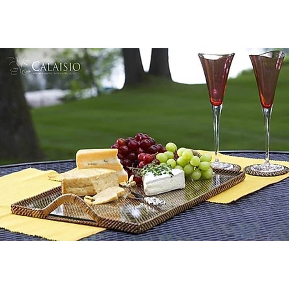 Rectangular serving tray with a glass bottom, featuring cheese, grapes, and two glasses on a textured surface.