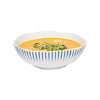 Sitio stripe coupe bowl in Delft blue with white stripes, filled with orange soup and garnished with herbs.